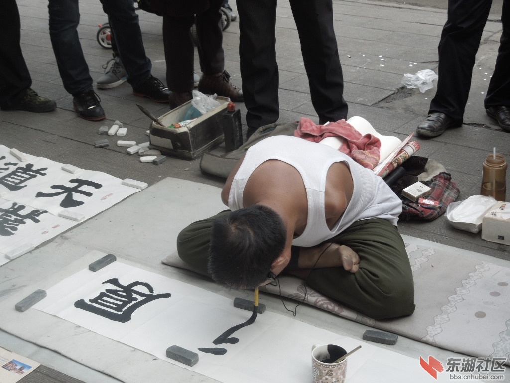 在汉正街看到一位双臂缺失的残疾人在街头写字乞讨,看他没有手,用嘴含
