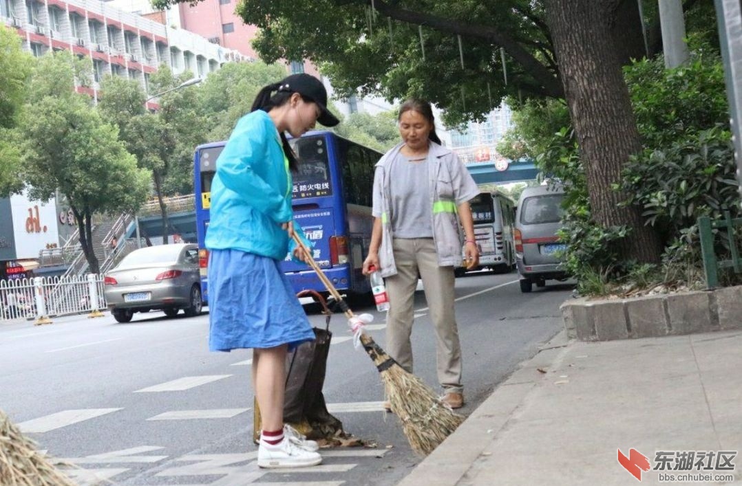 实践队队员帮助环卫工人清扫路边落叶