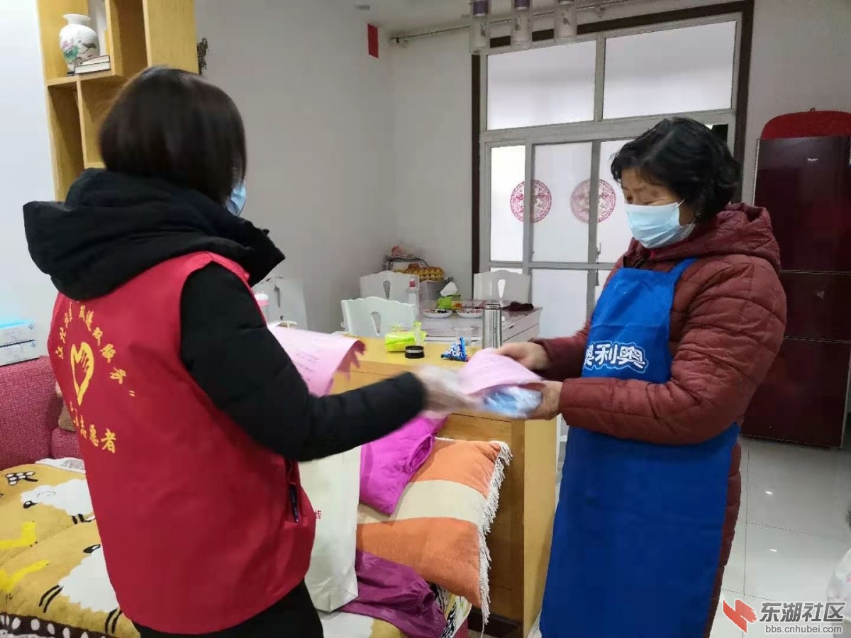 图为阳逻街高新社区工作人员发放一封信和口罩。